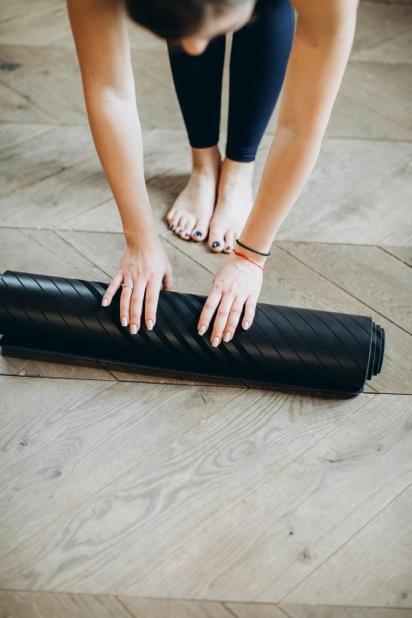 Woman rolling up a yoga mat, promoting natural wellness and holistic health remedies