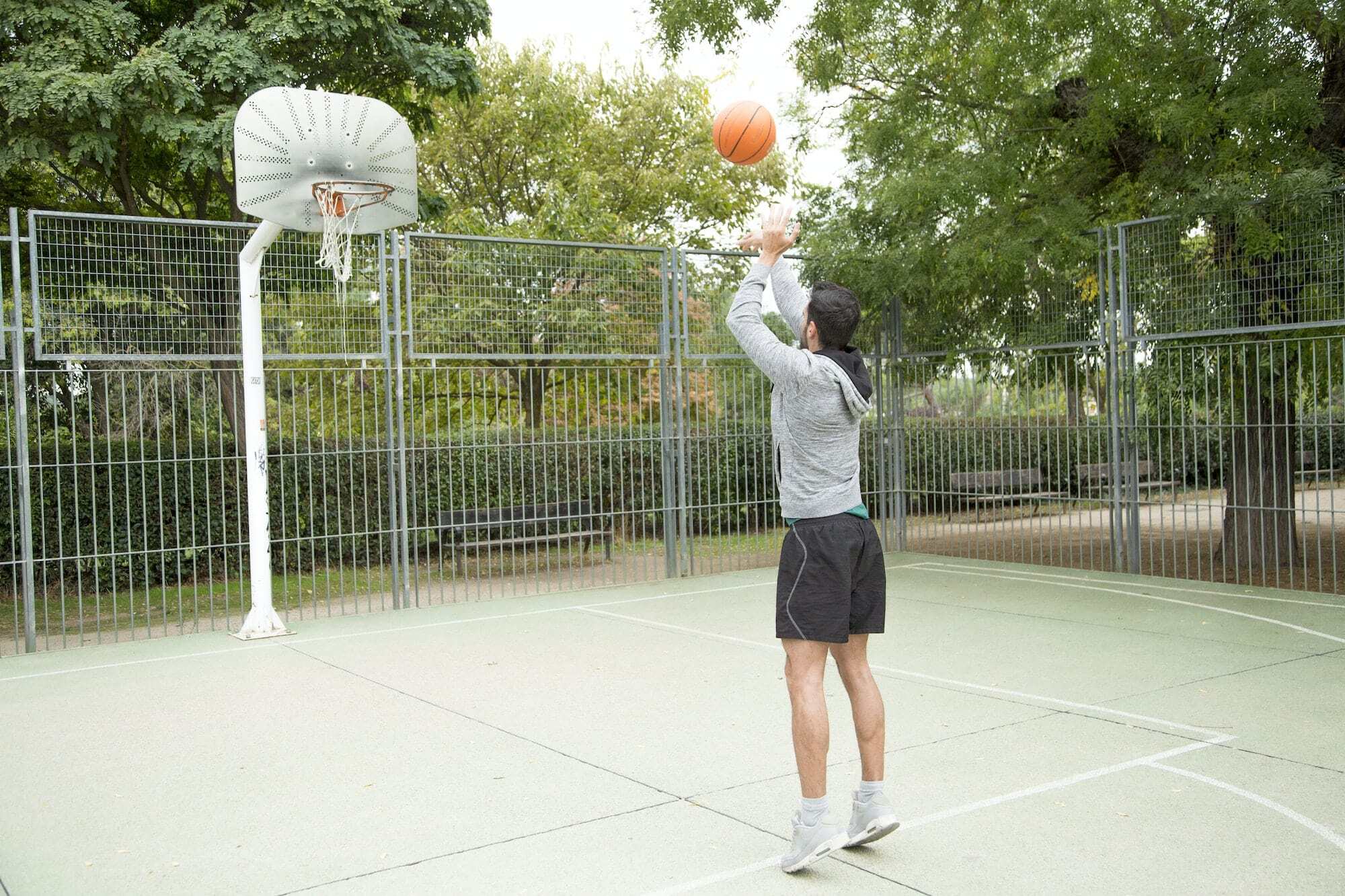 Man throwing a ball on an outdoor basketball court
