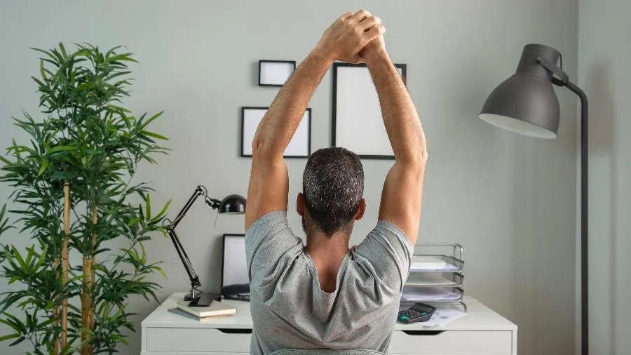 Person stretching at their desk to relieve work-from-home posture strain