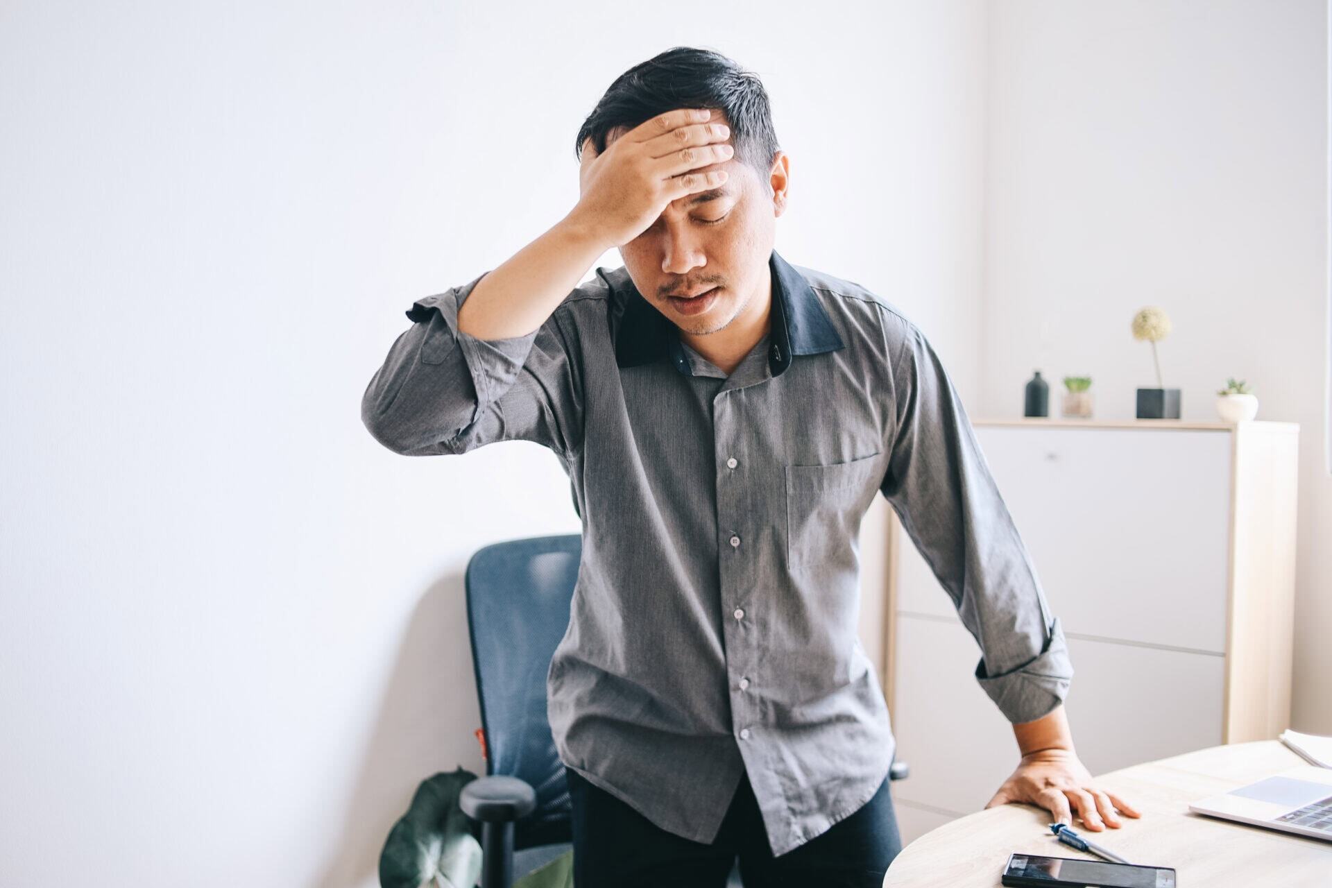 Man in office experiencing headache, potential chiropractic care candidate in Manhattan, NYC