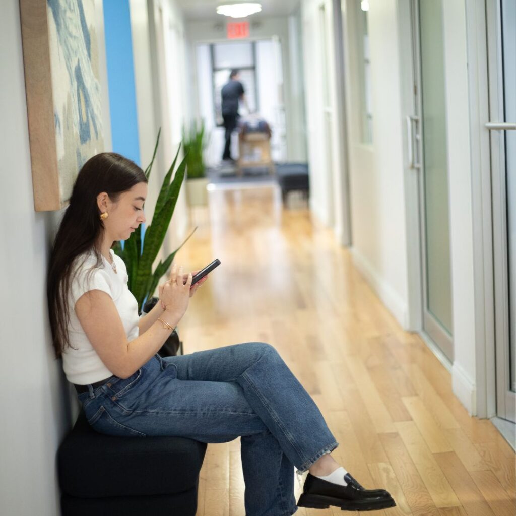 Chiropractic clinic hallway in Manhattan, NYC, with patient waiting and therapist preparing treatment room