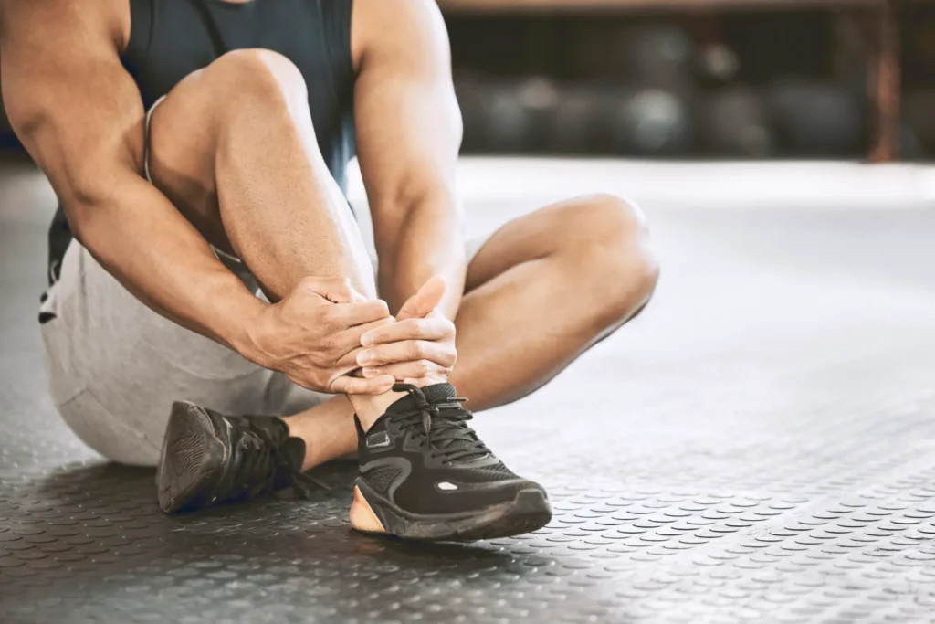 Man holding ankle, suggesting injury. Chiropractic and physical therapy services in Manhattan, NYC for recovery