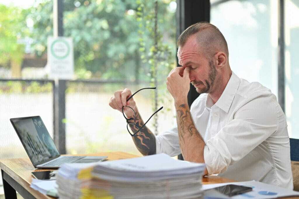 Overworked caucasian man worker holding glasses and rubbing nose