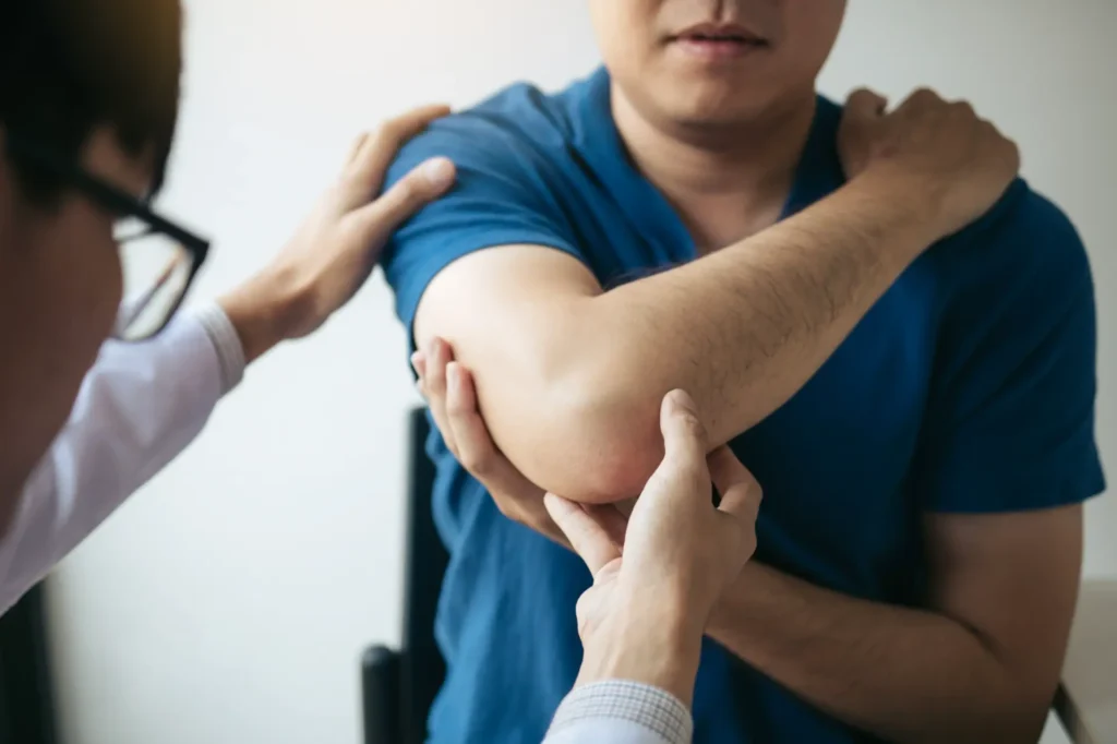 Chiropractor in NYC adjusts patient's elbow, highlighting physical therapy care in Manhattan clinic