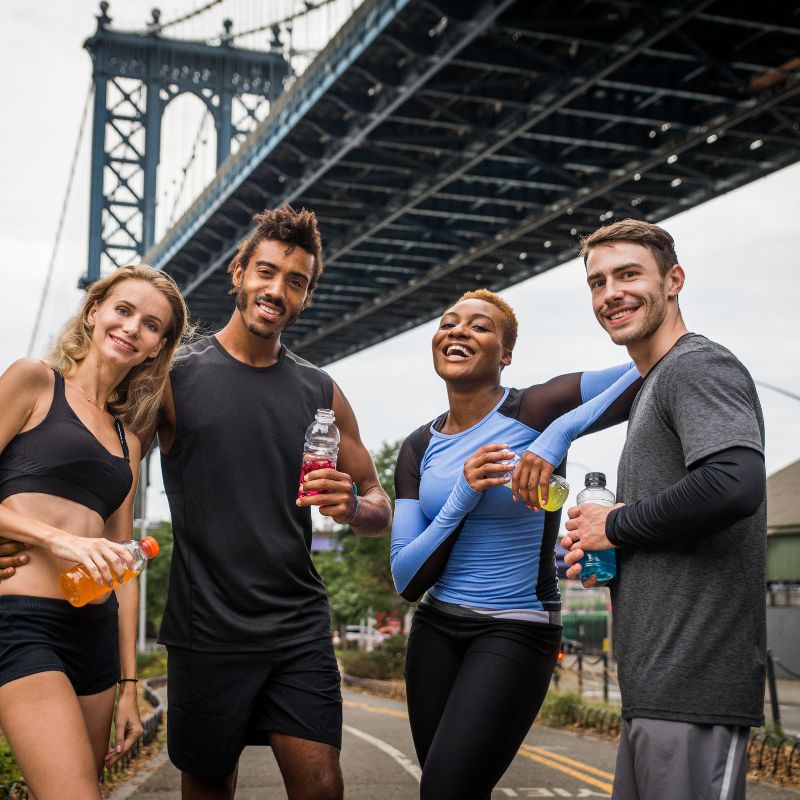 “Runners in NYC rehydrate with electrolyte drinks beneath the Manhattan Bridge during marathon prep.