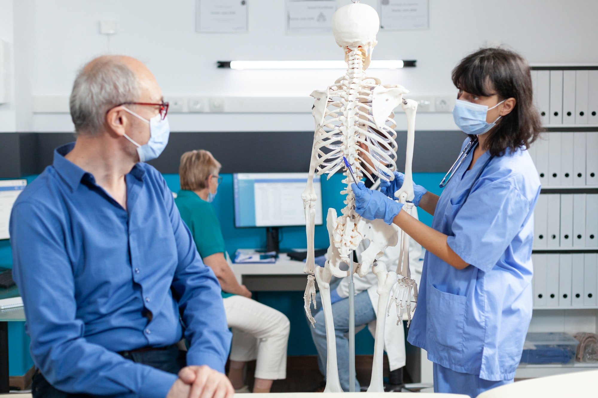 Older man looking at a skeleton model during chiropractic education