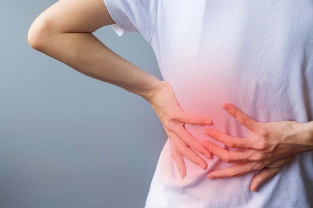 Woman holding lower back with discomfort while seated