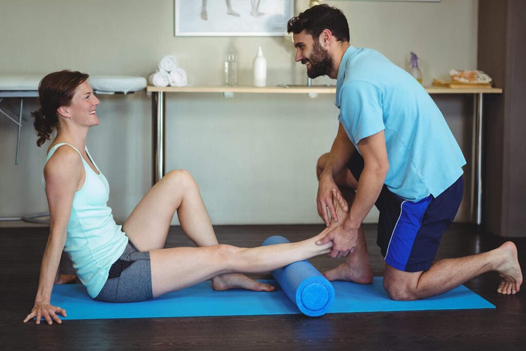 Chiropractor assists patient with leg therapy on mat in Manhattan clinic