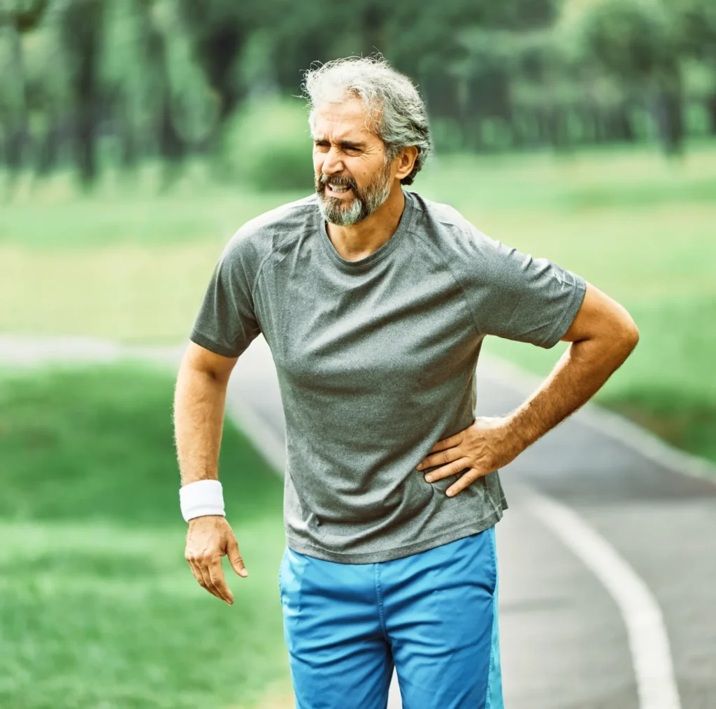 Man clutching lower back in pain, suitable for chiropractic or physical therapy treatment in Manhattan, NYC