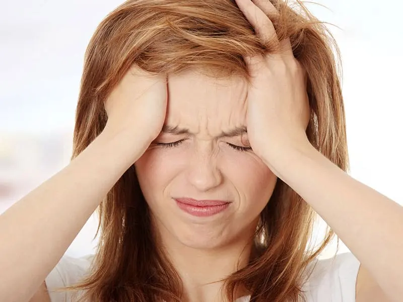 Woman looking stressed and frustrated, clutching her head.