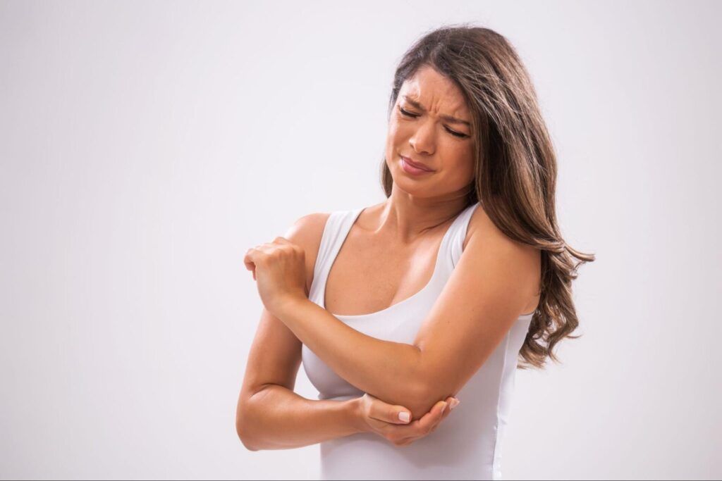 A woman holds her elbow in discomfort, highlighting need for chiropractic care in Manhattan, NYC