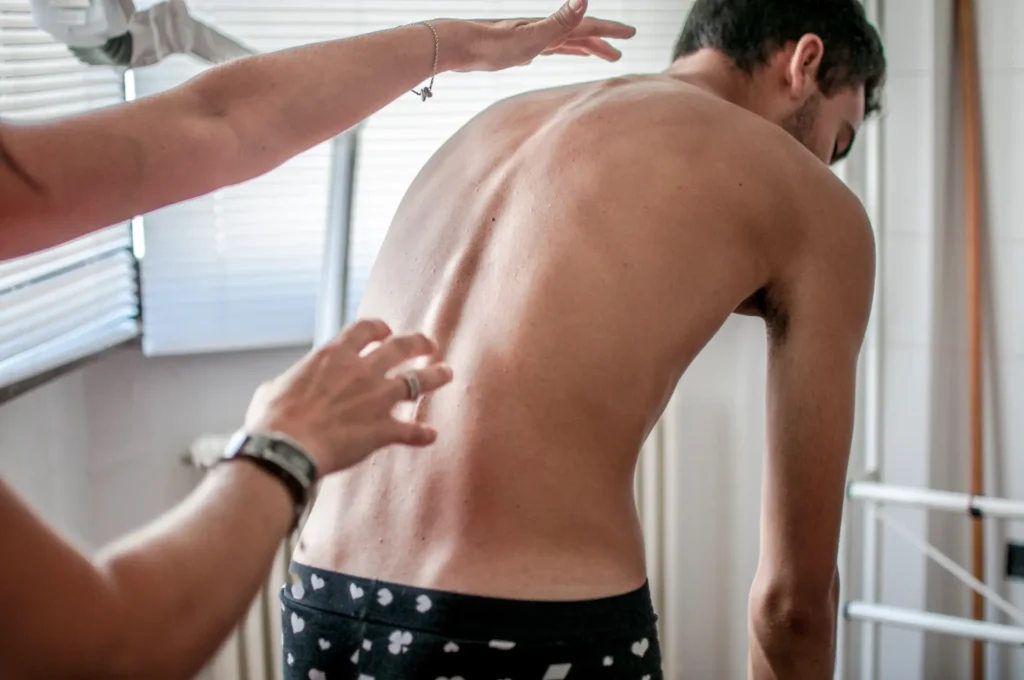 Chiropractor assessing patient's back posture in Manhattan NYC clinic