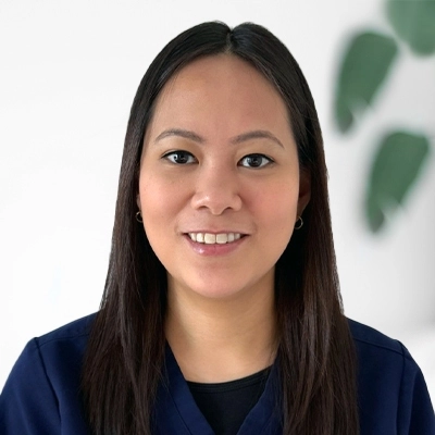 Smiling occupational therapist in navy scrubs at Prestige Health & Wellness, professional headshot against a white background with soft greenery.