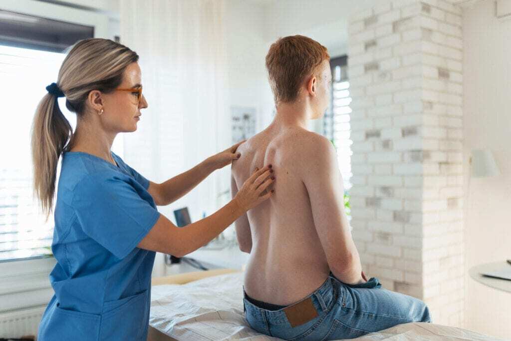 Chiropractor assessing patient's back in Manhattan clinic, NYC