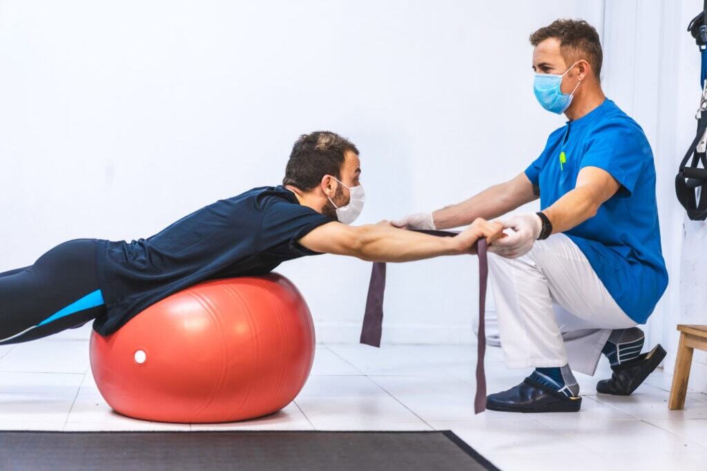 Chiropractor assists patient on exercise ball during therapy session in Manhattan, NYC clinic