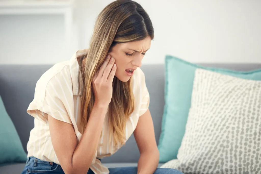 A woman experiencing jaw pain, potentially seeking chiropractic care in Manhattan, NYC