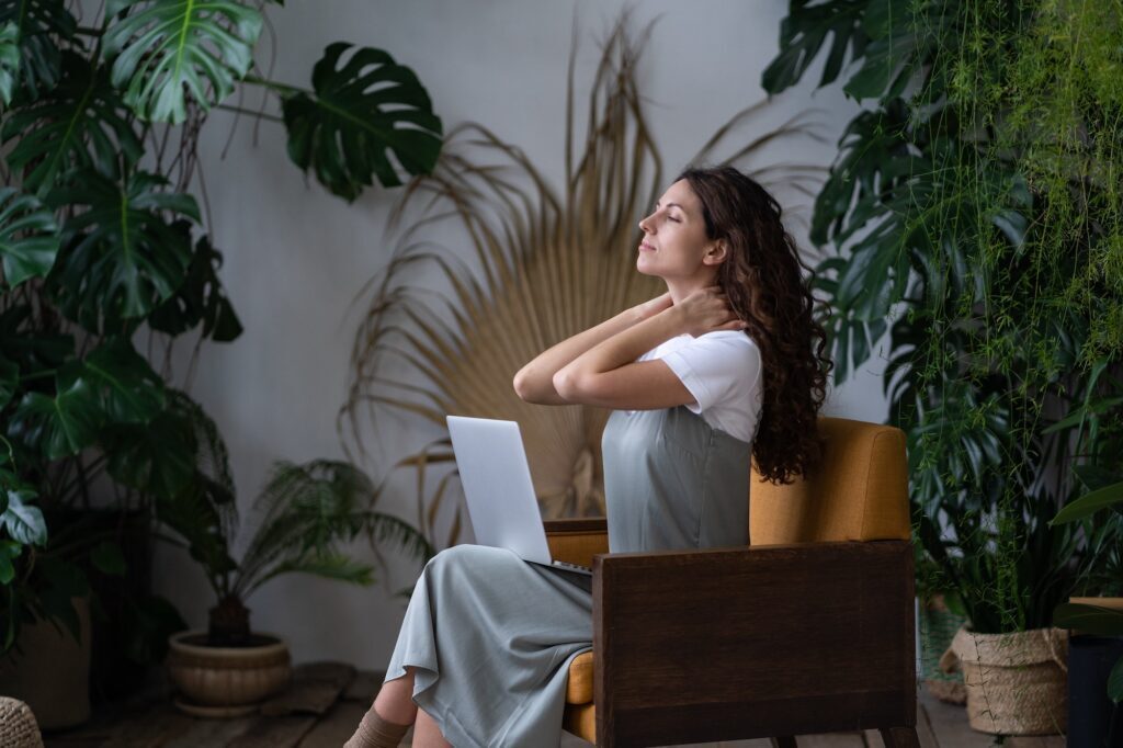 Remote worker massaging neck while seated in a home office