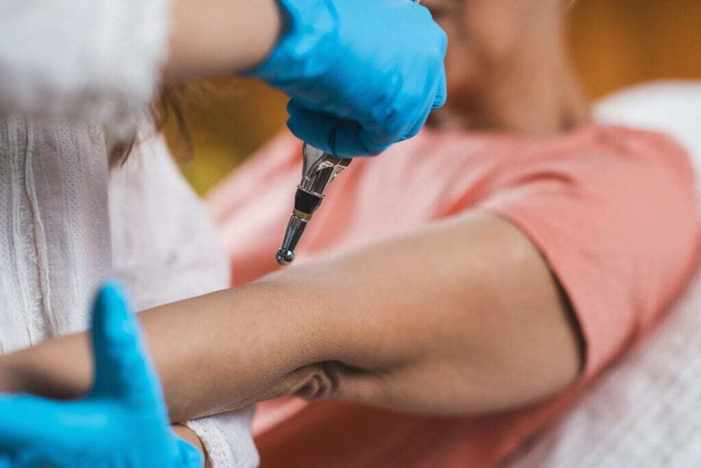 Practitioner using a therapy tool on a patient’s elbow area