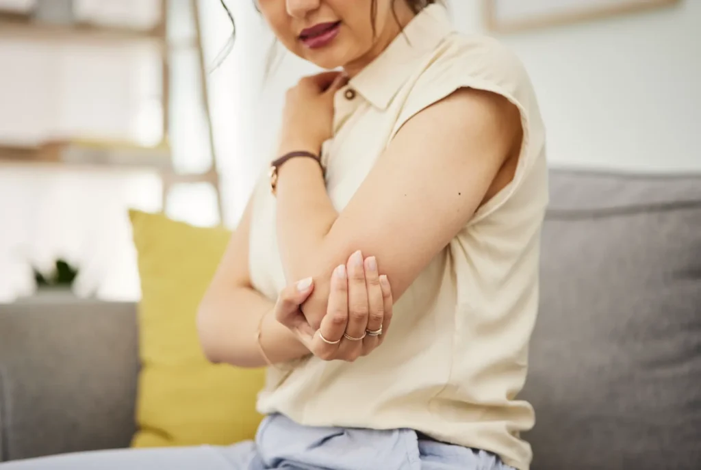 Person holding elbow in pain, seeking chiropractic or physical therapy care in Manhattan, NYC