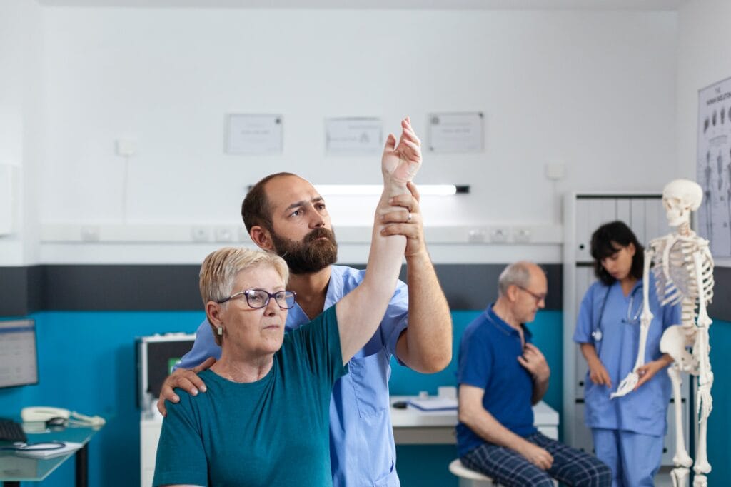 Chiropractor holding arm of old woman to relieve pressure