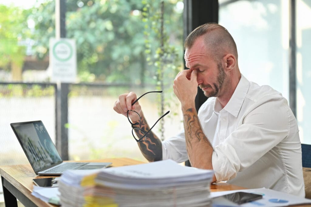 Overworked caucasian man worker holding glasses and rubbing nose