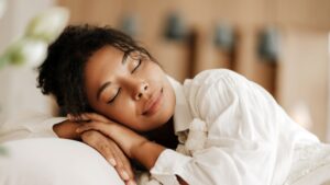 Young woman sleeping peacefully in a quiet NYC bedroom with blackout curtains.